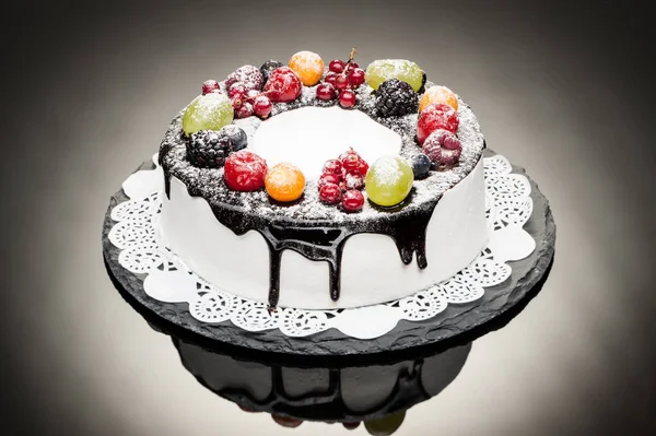 chocolate berry cake on stone plate over black background