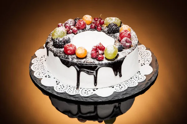 chocolate berry cake on stone plate over orange background