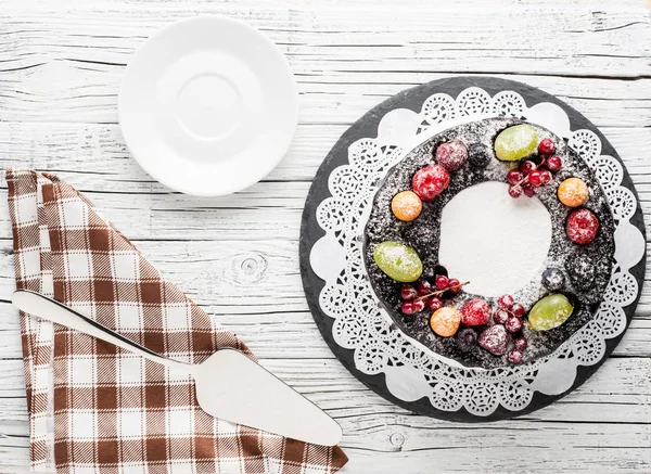 chocolate berry cake on plate over white wooden background