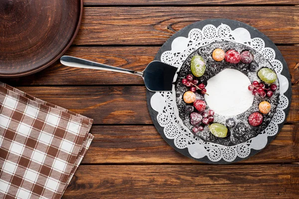 chocolate berry cake on plate over brown wooden background