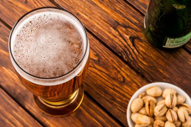 galss soğuk köpüklü lager bira, fındık, şişe, eski ahşap masa