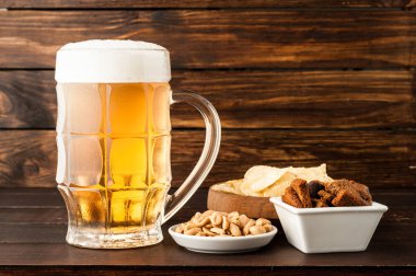 bardak soğuk köpüklü lager bira ve ahşap masa snacks