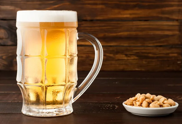 bardak soğuk köpüklü lager bira ve fıstık plaka üzerinde ahşap tabl