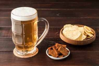 soğuk köpüklü lager bira ve cips plaka üzerinde ahşap bardak