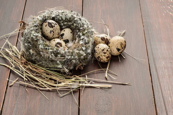 Quail eggs in a nest over old wooden background — Stock Photo, Image