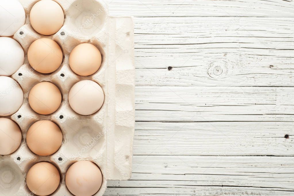 chicken eggs in cardboard box on white wooden background