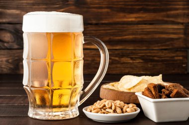 bardak soğuk köpüklü lager bira ve ahşap masa snacks