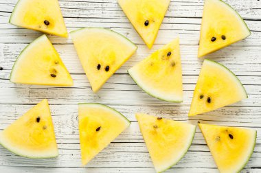 Beyaz ahşap zemin üzerine sarı karpuz dilimleri görünümü top
