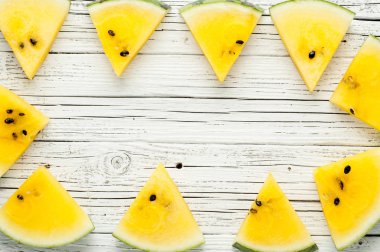 Beyaz ahşap zemin üzerine sarı karpuz dilimleri görünümü top