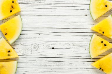 Beyaz ahşap zemin üzerine sarı karpuz dilimleri görünümü top