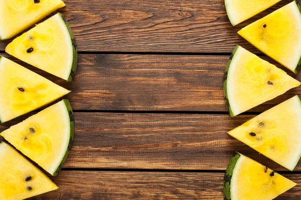 yellow watermelon slices on dark old wooden background top view