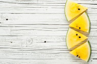 Beyaz ahşap zemin üzerine sarı karpuz dilimleri görünümü top