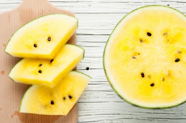 Beyaz ahşap zemin üzerine sarı karpuz dilimleri görünümü top