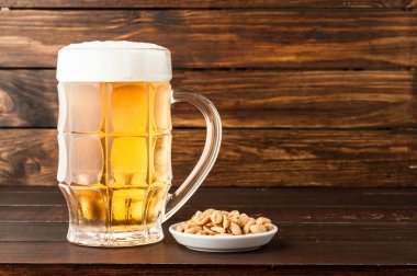 bardak soğuk köpüklü lager bira ve ahşap masa snacks
