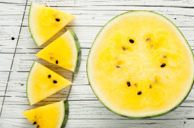 Beyaz ahşap zemin üzerine sarı karpuz dilimleri görünümü top