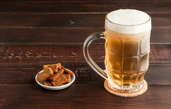 Склянка холодного пива і тарілка закусок на дерев'яній тарілці — стокове фото
