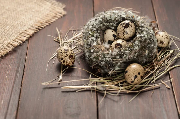 Quail eggs in a nest over old wooden background — Stock Photo, Image