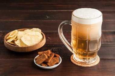 soğuk köpüklü lager bira ve cips plaka üzerinde ahşap bardak