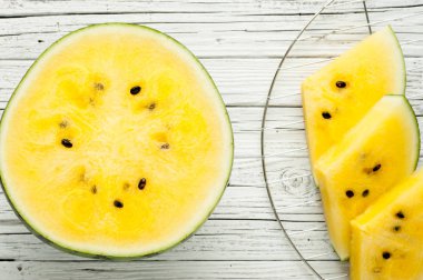 Beyaz ahşap zemin üzerine sarı karpuz dilimleri görünümü top