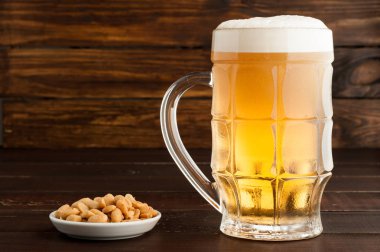 bardak soğuk köpüklü lager bira ve fıstık plaka üzerinde ahşap tabl