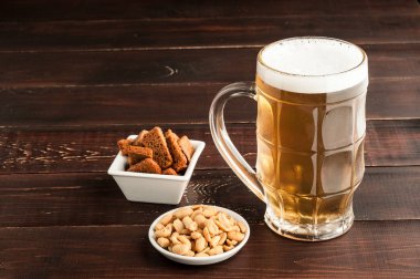 bardak soğuk köpüklü lager bira ve fıstık plaka üzerinde ahşap tabl