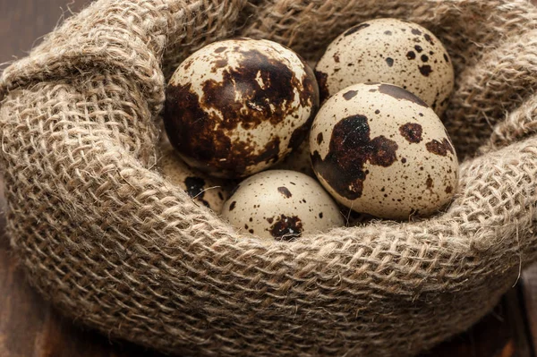 Перепелині яйця в мішковині на темному дерев'яному фоні — стокове фото