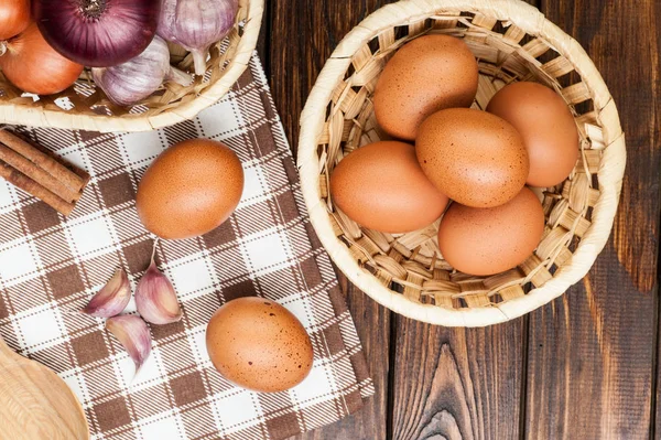 Chicken eggs in basket decorated with food ingredients on wooden Stock Photo