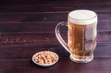 bardak soğuk köpüklü lager bira ve fıstık plaka üzerinde ahşap tabl