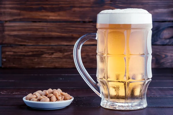 bardak soğuk köpüklü lager bira ve fıstık plaka üzerinde ahşap tabl