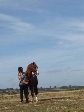 A beautiful young girl and her horse stand in the landscape on the Suffolk coast.