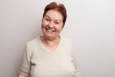 Beyaz arka planda, açık renk kazaklı yetişkin bir kadın. Duygular