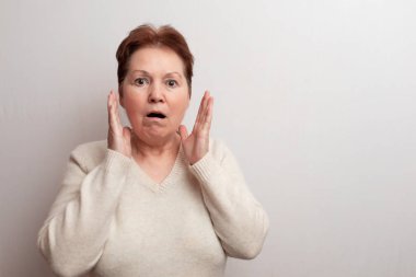 Beyaz arka planda, açık renk kazaklı yetişkin bir kadın. Duygular