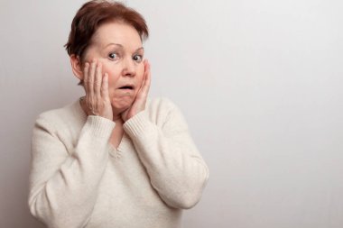 Beyaz arka planda, açık renk kazaklı yetişkin bir kadın. Duygular