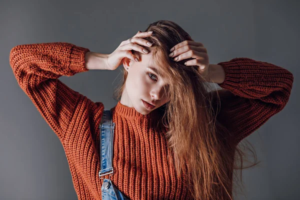 Jovem mulher atraente em uma camisola vermelha em um fundo cinza . — Fotografia de Stock