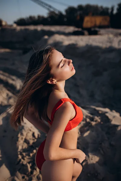 Beautiful fair-haired young girl in a red bathing suit on the beach — Stok fotoğraf