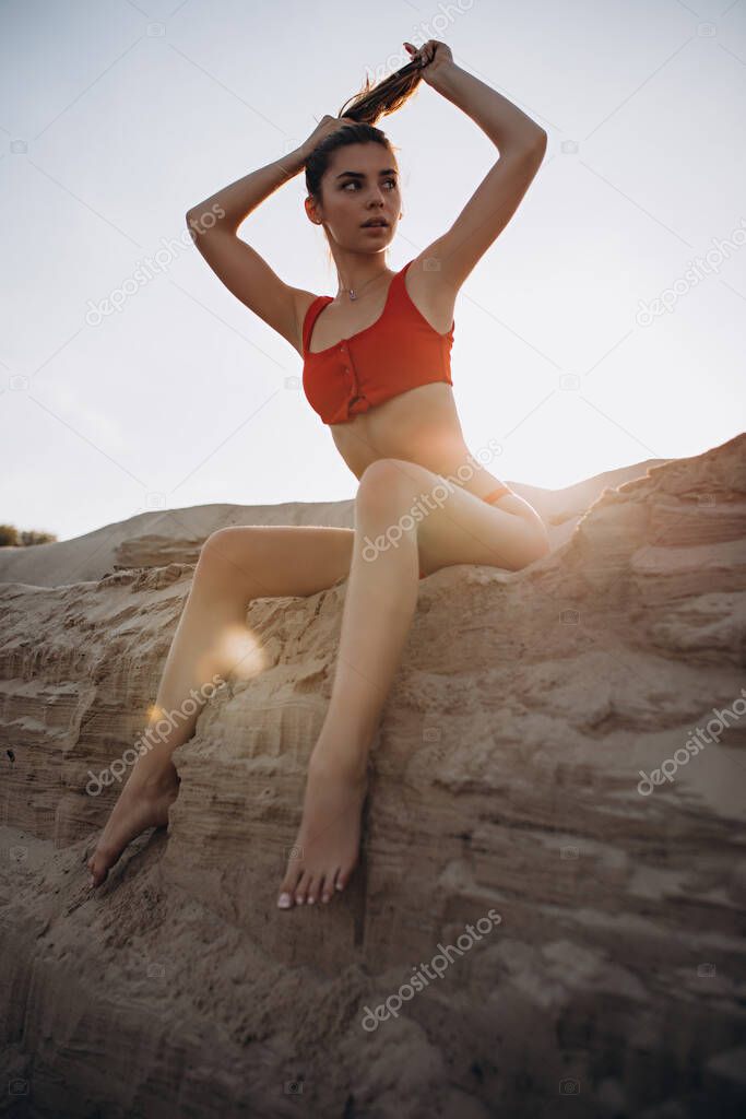 Beautiful fair-haired young girl in a red bathing suit on the beach