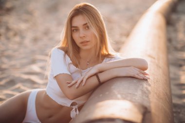 beautiful blond girl in a white swimsuit on the beach