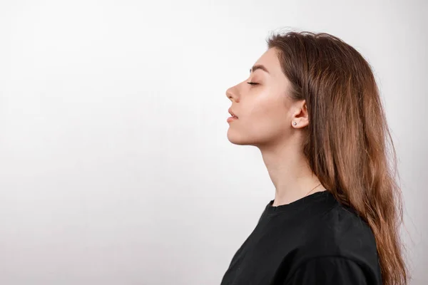 Beyaz arka plandaki güzel genç bir kadın siyah gömlekli bir profil çiziyor. çoklu uzay. izole et