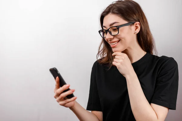 Hermosa Joven Sobre Fondo Blanco Mira Teléfono Con Gafas Una —  Fotos de Stock