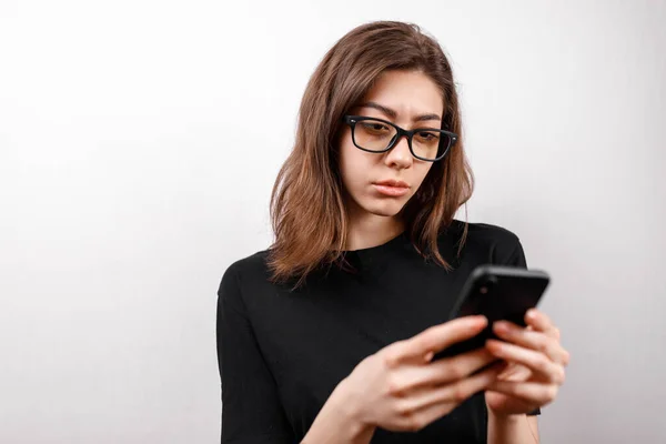 Hermosa Joven Sobre Fondo Blanco Mira Teléfono Con Gafas Una —  Fotos de Stock