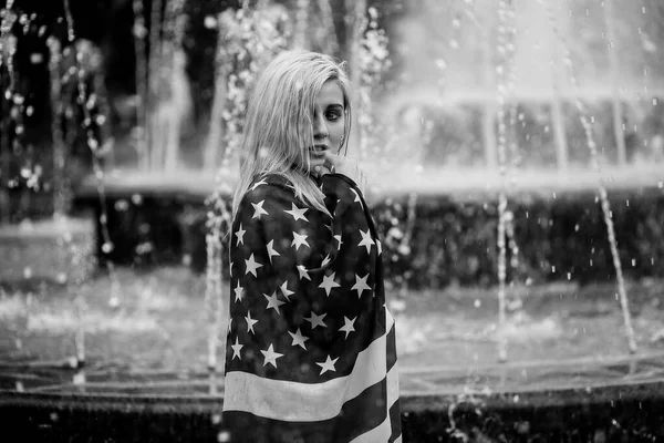 Красивая молодая блондинка на фоне города с американским флагом — стоковое фото
