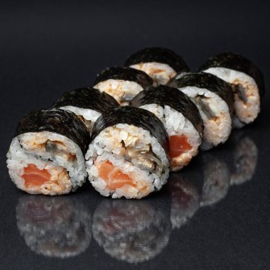 Siyah bir zemin üzerinde yansıması olan çeşitli lezzetli suşi ruloları. menü