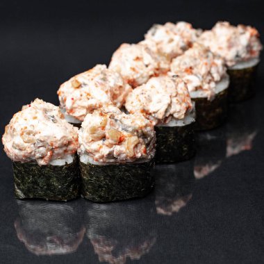 Siyah bir zemin üzerinde yansıması olan çeşitli lezzetli suşi ruloları. menü