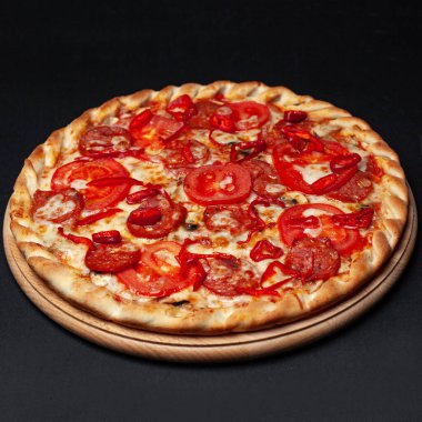 Siyah bir tabakta servis edilen nefis biberli pizza.