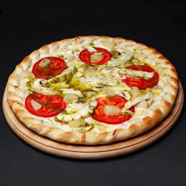 Delicious chicken pizza served on a wooden plate isolated on black