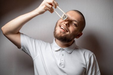 Genç adamın komik resmi beyaz arka planda suşi ruloları tutuyor. kopyala