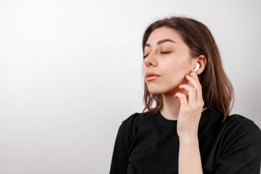 Beyaz arka planda siyah tişörtlü esmer kadın müzik dinliyor. izole