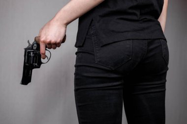 Siyah kotlu silahlı bir kız tabancasını arkasına saklar. Gizli tehdit. Katil kadın..