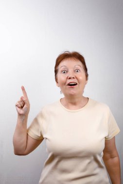 Güzel, son sınıf öğrencisi bir kadın beyaz bir arka planda, açık tişörtlü, duyguları olan bir el gösteriyor.