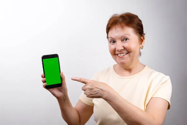 Mujer Mayor Muestra Teléfono Sobre Fondo Blanco Una Camiseta Ligera —  Fotos de Stock